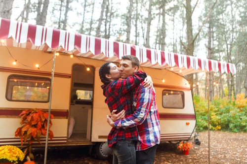 a couple hugging outside their travel trailer after downsizing for RV life